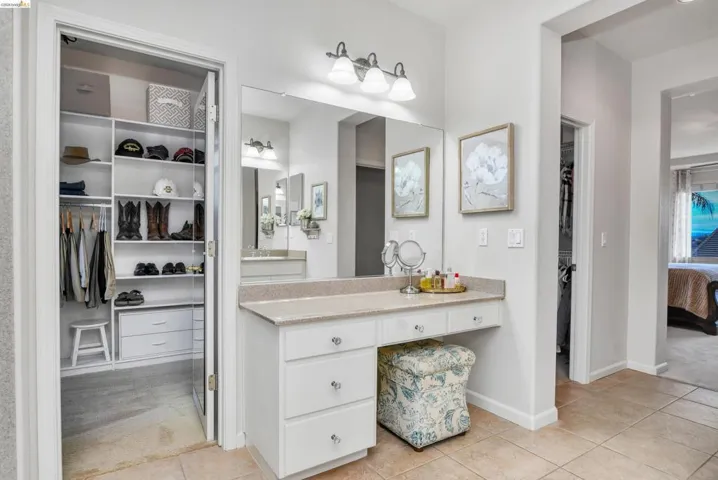 Ensuite bathroom with a spacious closet, vanity, and light tile patterned floors