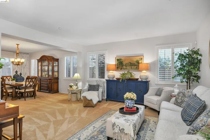 Living area featuring light colored carpet and suspended lighting