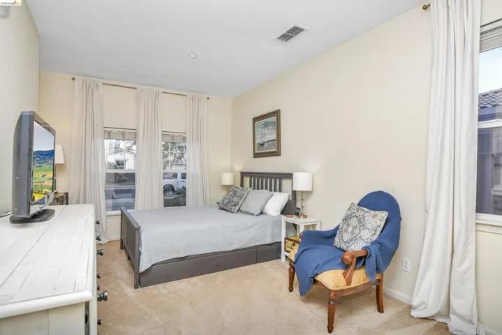 Bedroom with light carpet and multiple windows