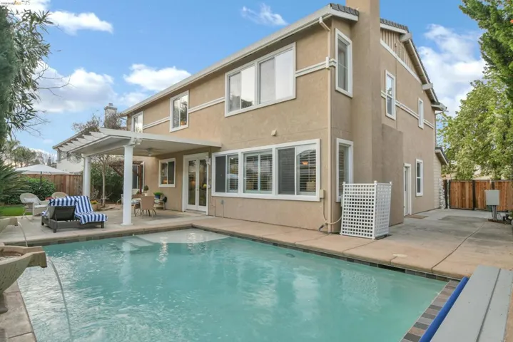 Rear view of house featuring a patio, french doors, stucco siding, ceiling fan, and a chimney