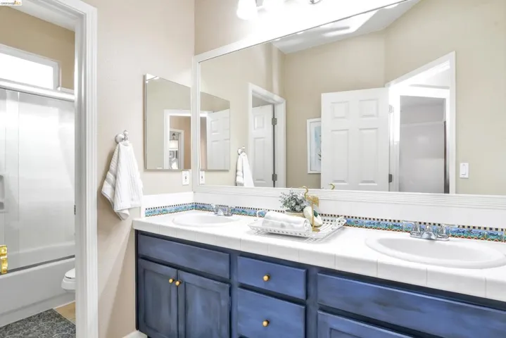 Bathroom with double vanity and combined bath / shower with glass door