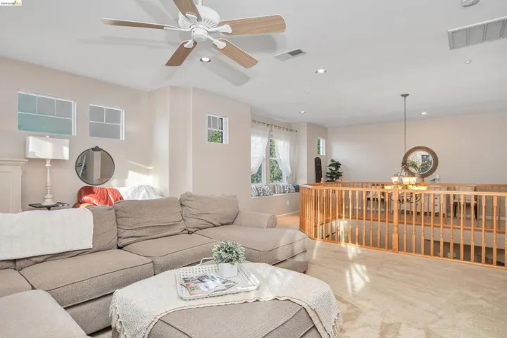 Carpeted living room with a ceiling fan and hanging lights