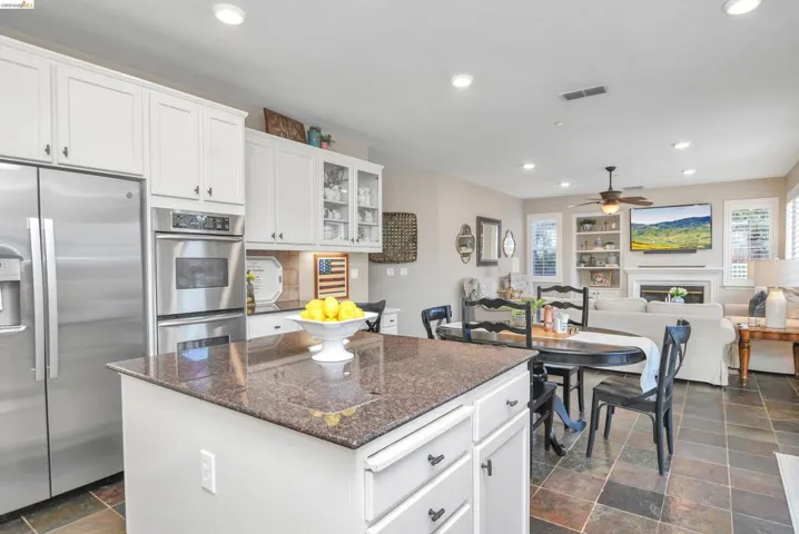 Kitchen featuring stainless steel appliances, a center island, white cabinetry, dark stone counters, and recessed lighting