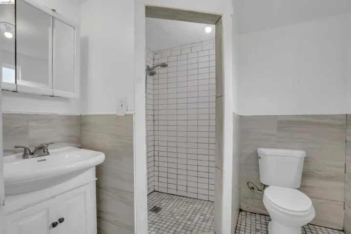 Bathroom with tile walls, vanity, a wainscoted wall, a stall shower, and light tile patterned flooring