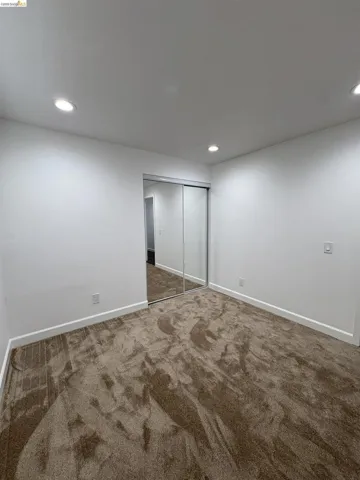 Unfurnished bedroom with dark carpet, a closet, and recessed lighting