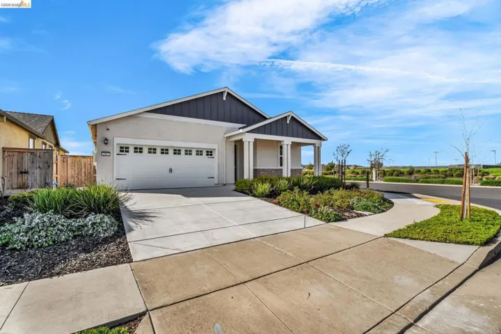 View of front facade with driveway, an attached garage, stucco siding, and board and batten siding