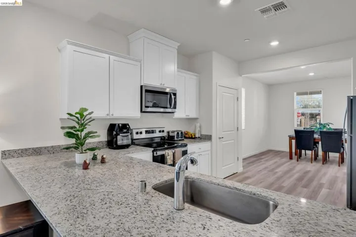 Kitchen featuring white cabinetry, stainless steel appliances, light stone counters, light wood-style flooring, and recessed lighting