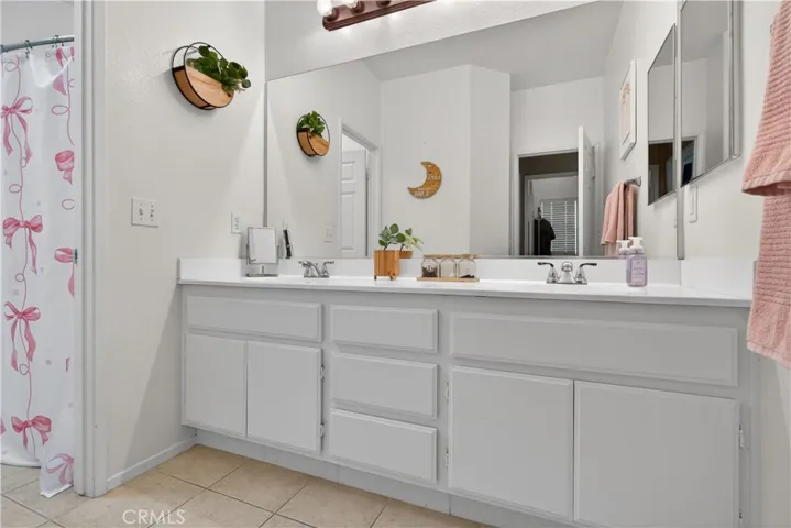 Bathroom #3: Spacious bathroom with double-sink vanity, large mirror, and ample cabinet storage. Features tile flooring and a shower/tub combo.