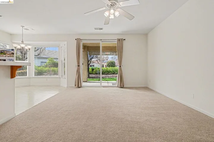 Unfurnished room featuring ceiling fan, light carpet, and a chandelier