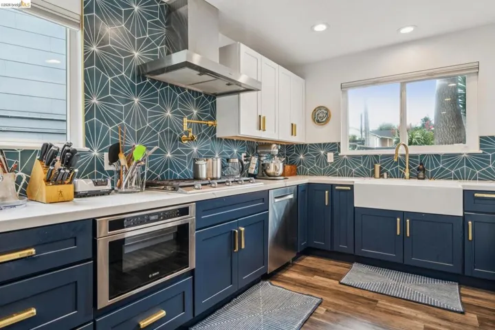 Two tone kitchen with two tone cabinetry, stainless steel appliances, tasteful backsplash, light stone counters, and recessed lighting