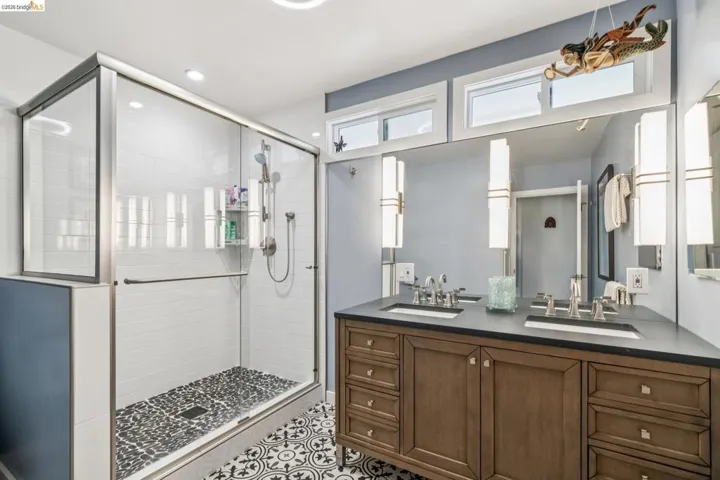 Bathroom with double vanity, a stall shower, and light tile patterned floors