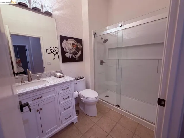 Full bathroom featuring a textured wall, vanity, and a stall shower