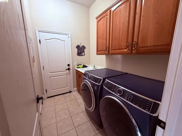 Laundry area with cabinet space, light tile patterned flooring, and separate washer and dryer