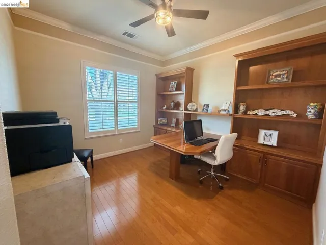 Office area with light wood-style floors, ornamental molding, ceiling fan, and built in shelves