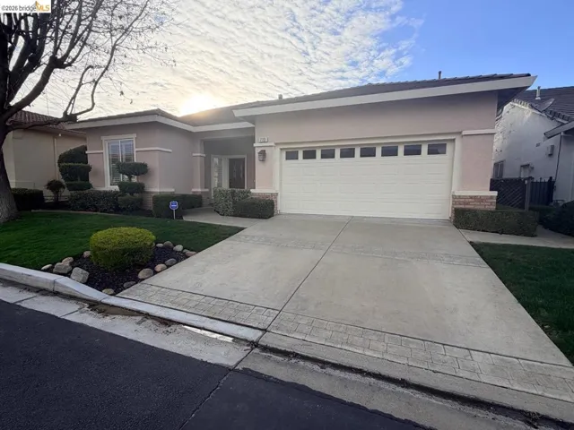 Single story home featuring stucco siding, driveway, a garage, and a front lawn