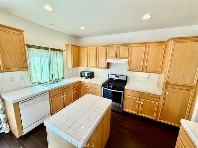 Island kitchen with recess lighting hardwood flooring and plenty of natural light