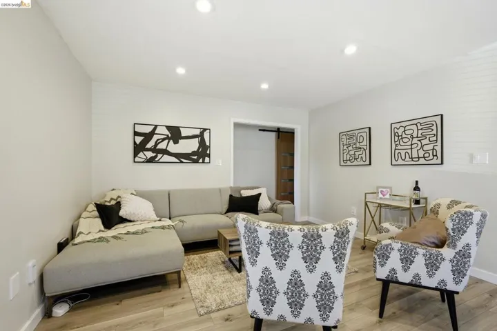Living area with recessed lighting, light wood-style floors, and a barn door