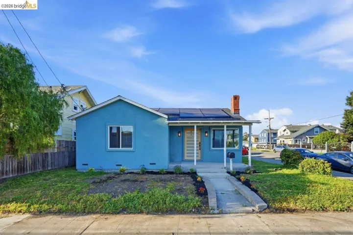 View of front of home with solar panels, a chimney, stucco siding, and a porch
