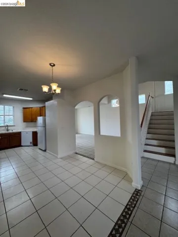Unfurnished dining area featuring arched walkways, hanging lights, and light tile patterned floors