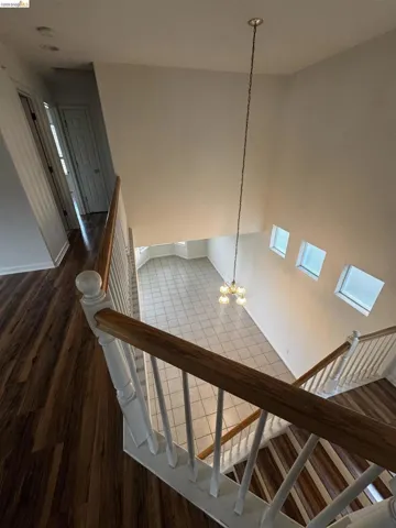 Stairs with suspended lighting, wood finished floors, and a high ceiling