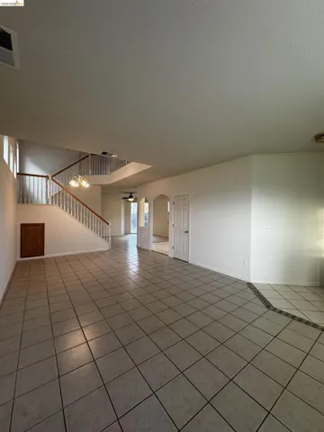 Empty room with light tile patterned flooring, arched walkways, and ceiling fan