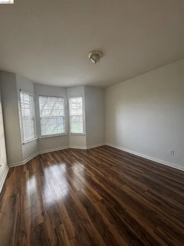 Unfurnished room with dark wood-type flooring and a textured ceiling