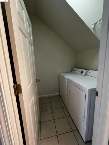 Laundry area featuring washing machine and dryer, light tile patterned flooring, and lofted ceiling