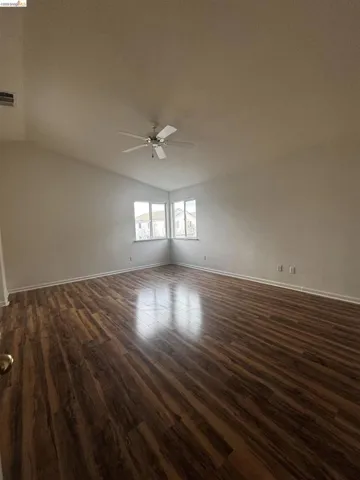 Spare room featuring ceiling fan, vaulted ceiling, and dark wood-type flooring