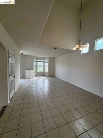 Spare room with light tile patterned floors, suspended lighting, and a high ceiling