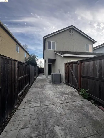 Back of house featuring a gate, stucco siding, a fenced backyard, and a patio area