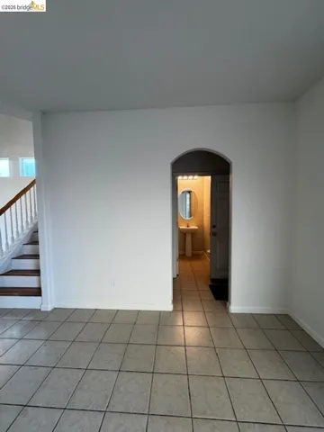 Unfurnished room with arched walkways and light tile patterned floors
