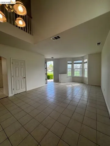 Unfurnished living room with light tile patterned floors and baseboards