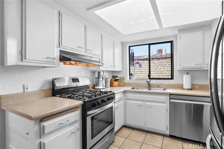 Unit #64 - Kitchen has Corian counters, white cabinets, gas range with hood vent.
