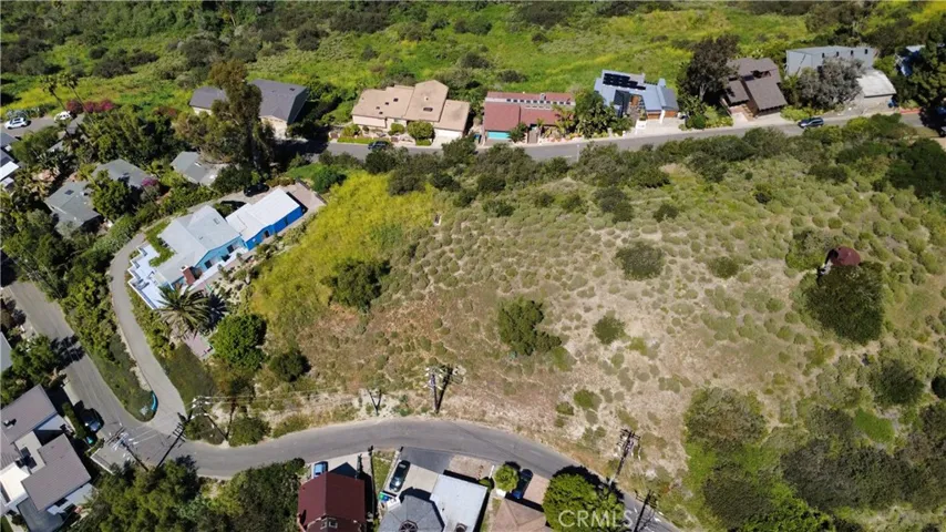 Elevated aerial perspective showcasing the full homesite, highlighting the generous lot size and its position within a quiet, established coastal neighborhood.