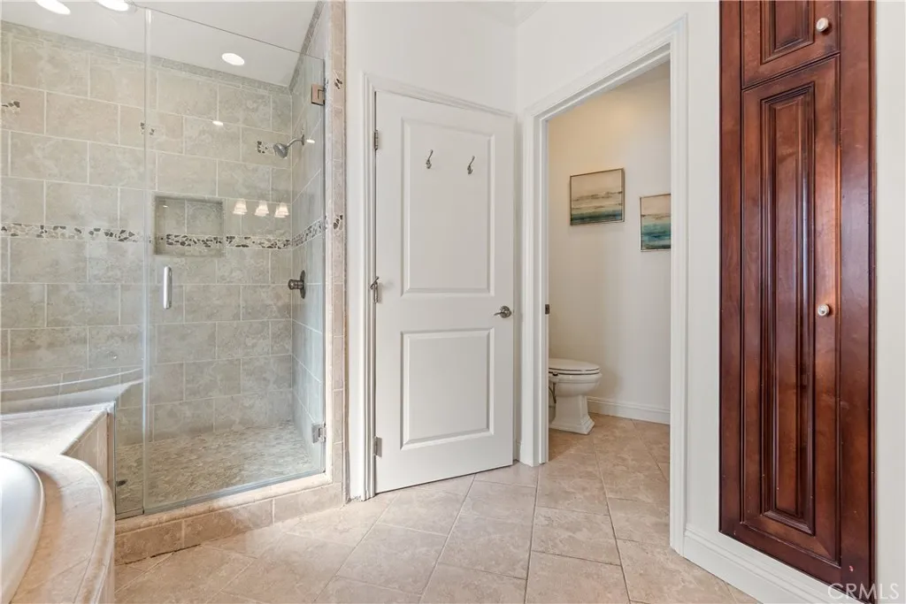 Well-appointed primary bathroom with custom wood vanity, dual sinks, soaking tub, and elegant stone surfaces.