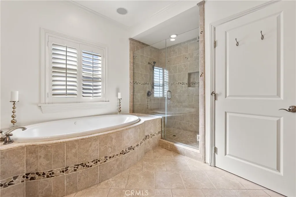 Well-appointed primary bathroom with custom wood vanity, dual sinks, soaking tub, and elegant stone surfaces.