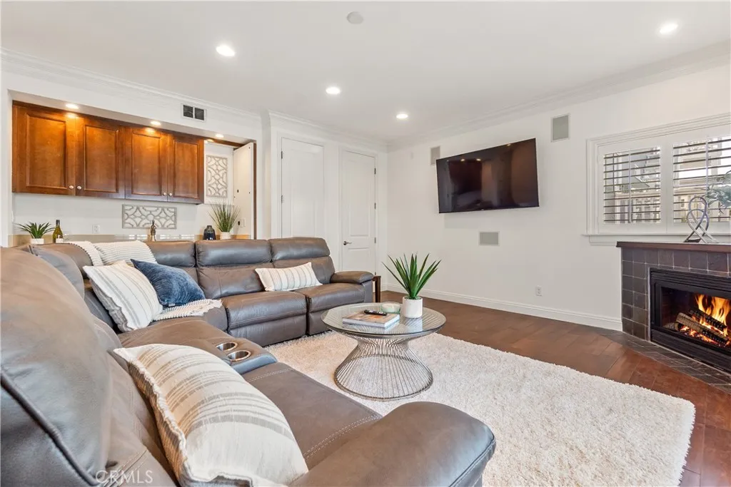 Inviting, light-filled living room opening to the balcony, featuring a beautiful wet bar with rich wood cabinetry.