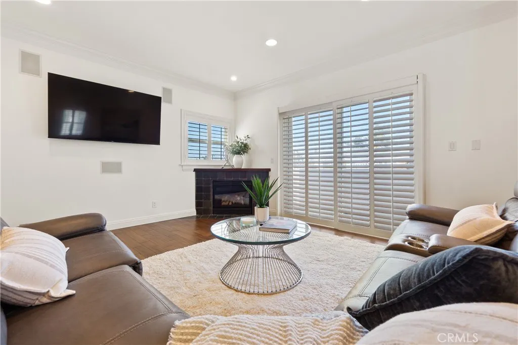 Spacious and inviting living room with rich hardwood floors, fireplace, and a beautiful built-in wet bar with wood cabinetry, offering a comfortable setting with an open and functional layout for everyday living and entertaining.