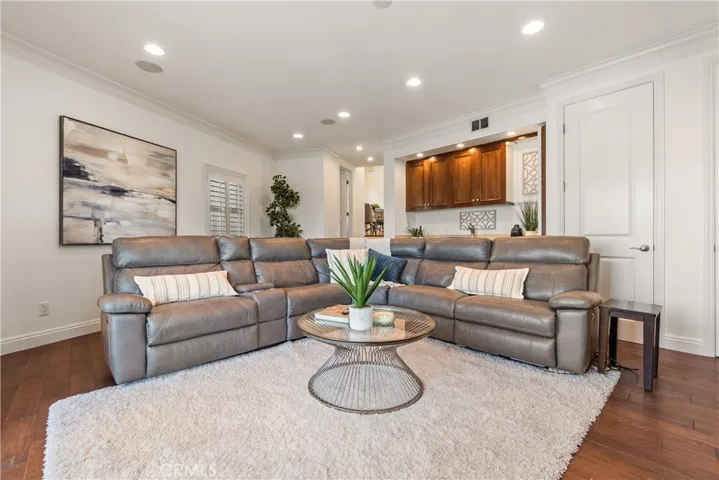 Spacious and inviting living room with rich hardwood floors, fireplace, and a beautiful built-in wet bar with wood cabinetry, offering a comfortable setting with an open and functional layout for everyday living and entertaining.
