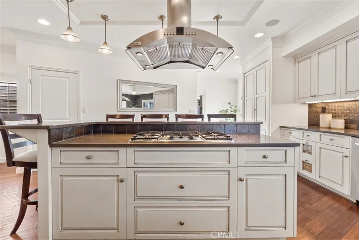 Beautifully designed kitchen with stainless steel appliances and a large center island with integrated gas range and seating, offering both style and versatility.
