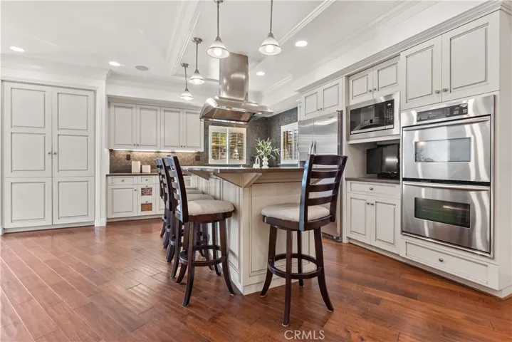 Beautifully appointed kitchen featuring stainless steel appliances and a generous center island with integrated gas range and counter seating, combining refined design with everyday functionality.