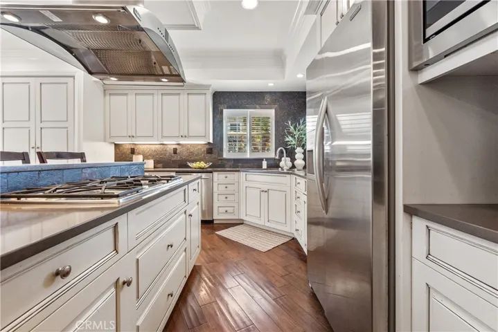 Beautifully designed kitchen with stainless steel appliances and a large center island with integrated gas range and seating, offering both style and versatility.