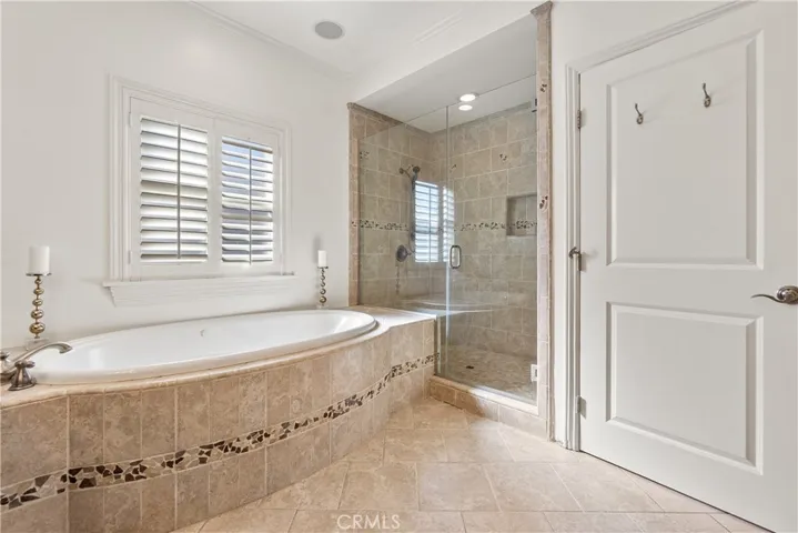 Well-appointed primary bathroom with custom wood vanity, dual sinks, soaking tub, and elegant stone surfaces.