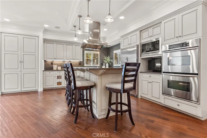 Beautifully appointed kitchen featuring stainless steel appliances and a generous center island with integrated gas range and counter seating, combining refined design with everyday functionality.
