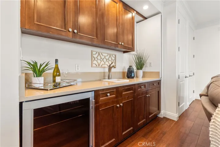 Inviting, light-filled living room opening to the balcony, featuring a beautiful wet bar with rich wood cabinetry.