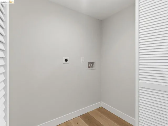 Laundry area with hookup for a washing machine, light wood finished floors, and hookup for an electric dryer