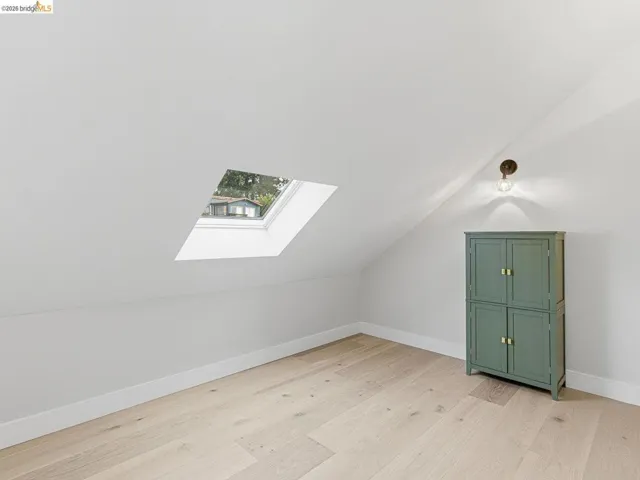 Bonus room featuring a skylight, light wood-style floors, and vaulted ceiling