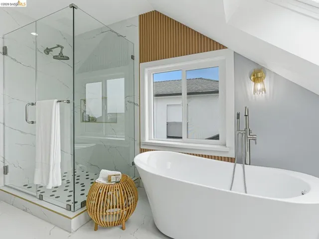 Bathroom with a marble finish shower, a freestanding bath, and lofted ceiling