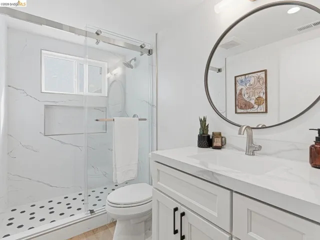 Full bathroom with vanity, a marble finish shower, and light wood-type flooring