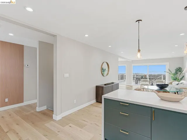 Kitchen with light stone countertops, open floor plan, light wood-style floors, and hanging light fixtures